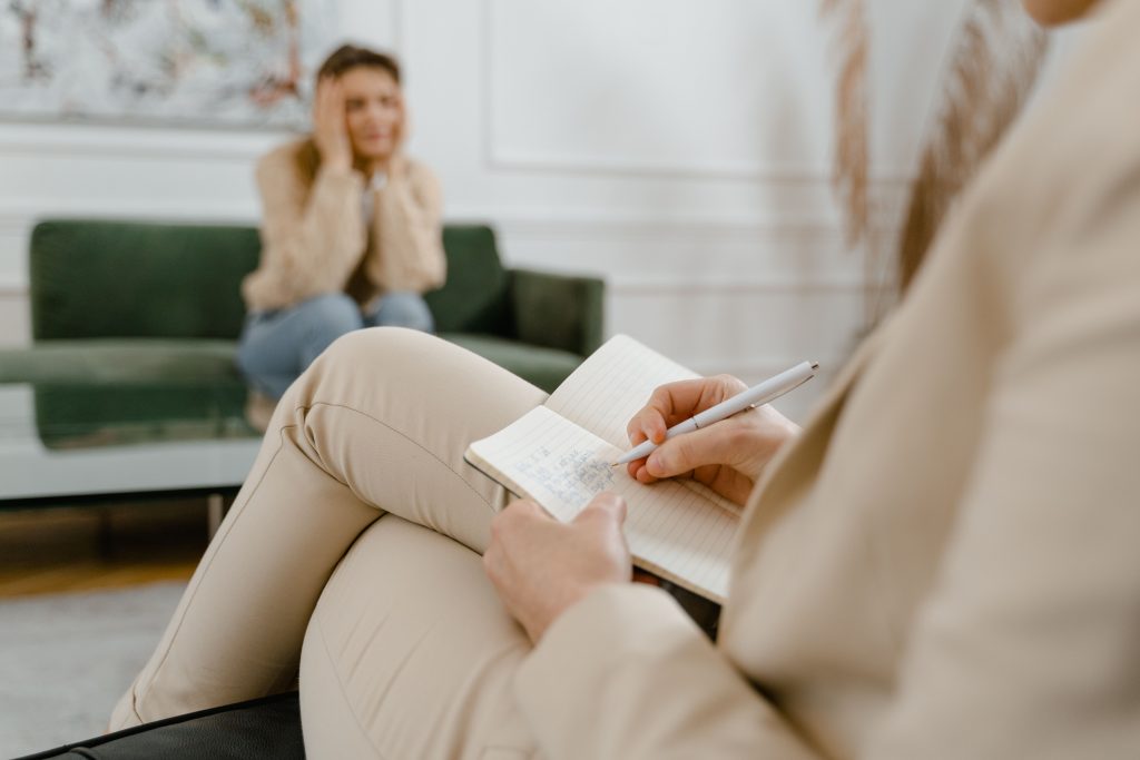 Therapist taking notes while a client sits across the room during a session